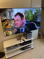 Samsung 65" QLED TV mounted on wall above media center, screen on