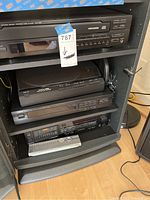 Yamaha and Denon audio equipment inside the wooden cabinet, including the CD player, tape player, stereo tuner, and remote on bottom shelf.
