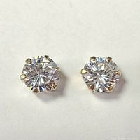 Pair of yellow gold stud earrings each with a round 6.5mm cubic zirconia stone secured by six prongs, shown on white background.