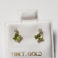 Pair of 10K yellow gold earrings with light green square-cut peridot gemstones and small round diamonds shown on white holder with 10KT GOLD stamp.