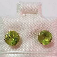 Front view of both peridot earrings showing round faceted green stones in yellow gold prong settings.