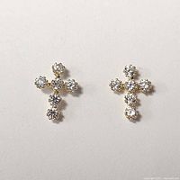 Front view of two 14K yellow gold earrings shaped as crosses, each set with round cubic zirconia stones.
