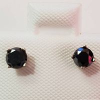 Front view of pair of black diamond stud earrings in 14K white gold on textured white display