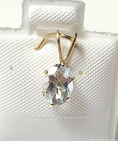 Close-up photo of the oval aquamarine stone pendant set in 14K yellow gold filled metal from front view
