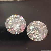 Close-up view of two round cut moissanite stones showing prism light reflections.
