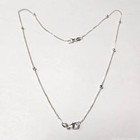 Photo showing the entire length of the silver necklace with bead accents laid flat showing clasp.