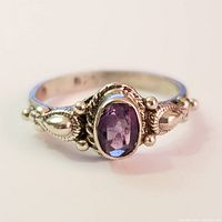 Close-up front view of silver ring with amethyst gemstone and decorative silver beadwork on band.