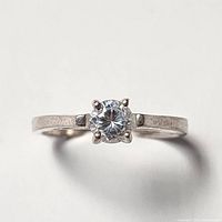 Close-up front view of silver ring with round clear cubic zirconia stone held by four prongs