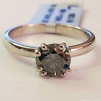 Close-up of the silver band with round-cut moissanite stone held by six prongs.