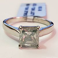 Front-facing close-up of the silver ring showing the square princess-cut moissanite stone and polished band.