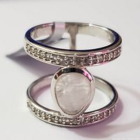 Close-up of pear-shaped moonstone set in bezel on open silver band with white topaz accents on sides
