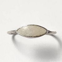 Close-up view of silver ring with marquise-shaped pale opal stone set in the center on a plain background.