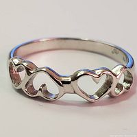 Front view of sterling silver ring with connected open heart shapes