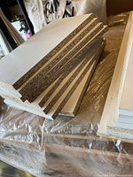 Stack of several white-wrapped particleboard off-cut pieces with raw particleboard edges and smooth white surfaces.