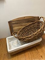 Top view showing all three items: rectangular basket with white fabric lining, oval basket placed inside it, and the wooden tray behind.