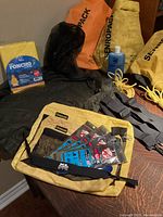 Camping lot items including dry bags, bug netting, bug repellent straps, shampoo, poncho, glasses strap and spoon