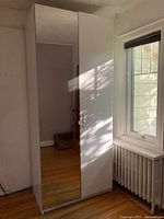 IKEA PAX wardrobe unit with mirrored door showing overall condition and size in natural room setting.