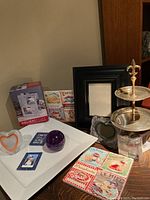 Photo showing the large white ceramic plate, paperweight, trivets, salt and pepper shakers, silver two-tiered treat holder and several picture frames