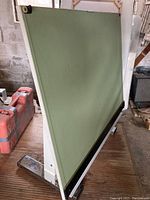 Drafting table with green slanted surface, chrome heavy base, integrated straight edge at bottom