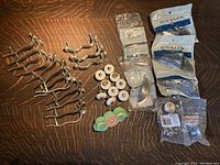 Wide shot showing all knobs and pulls laid out on a wooden surface, including pewter finish handles, porcelain knobs, and packaged hardware.