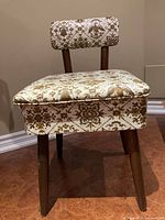 Side angled view of the sewing chair showing wooden legs and fabric upholstery