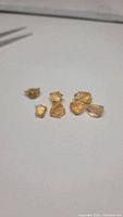 Seven golden citrine crystals arranged on a white surface, showing natural rough crystal shapes and clear golden color.