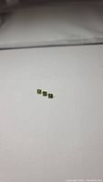 Three small square cut apple green peridot gemstones on white background