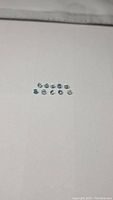 Ten small round diamond cut blue aquamarine stones arranged in two rows on a white background.