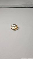 Oval natural golden citrine gemstone laid on white background, showing top and side facets.