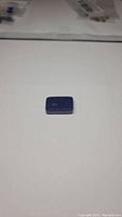 Solid rectangular deep blue lapis lazuli gemstone on white background, showing front top face and natural speckling.