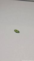Photo of a marquis cut natural peridot gemstone showing its apple green color on a plain background