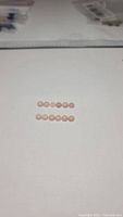 Twelve round pink opal cabochons arranged in two rows on white background.