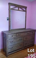 Front view of the dresser and attached tall mirror against a pink wall, showing the wood texture and drawer layout.