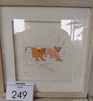 Full view of framed serigraph showing Simba and Nala from The Lion King with white matting and light wood frame.
