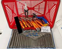 Photo showing red plastic shopping basket filled with multiple types of hand tools including pliers with high-vis handles, wrench, screwdriver, fittings and hex key set in pouch.