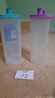 Photo showing two translucent rectangular plastic jugs with teal and purple lids standing upright.