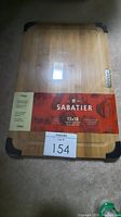 Photo shows Sabatier wooden cutting board in original packaging with black corner guards and size label of 12x18 inches.