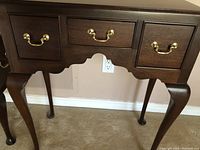 Front view showing three drawers with brass bail pulls and Queen Anne style cabriole legs