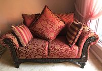 Front view of the Victorian Chesterfield loveseat with cushions showing red and gold damask upholstery pattern and dark wood carved frame.