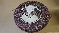 Top view of circular African drum table, showing detailed hand-painted giraffe artwork and scalloped pattern around the edge.