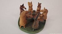 Front angle showing seven carved wooden animal figurines seated around a carved wood table on an oval base