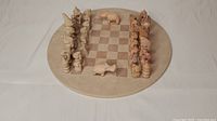 Full front view of the chess set showing round stone board and all carved pieces set up for play