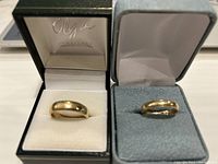 Both rings displayed in separate boxes; left black box holds 14 kt band, right gray box holds 10 kt band