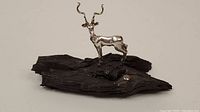 Front view of silver kudu figure standing on dark wood base