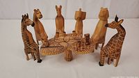 Wide shot showing all seven animal figurines sitting around the carved wooden table.