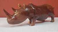Front angle view of the wooden rhino carving showing detailed face and front horn.