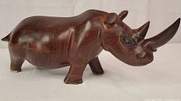 Side view of the brown polished wooden rhino carving showing the body and general shape.