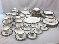 Full set arranged on table: stacks of plates, bowls, cups, saucers, teapot, sugar bowl, creamer, platter