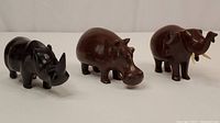 Photo of all three wooden animal carvings: rhinoceros, hippopotamus, and elephant, showing size and craftsmanship.