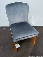 Front view of small occasional chair with gray upholstery and wooden legs against a white background.